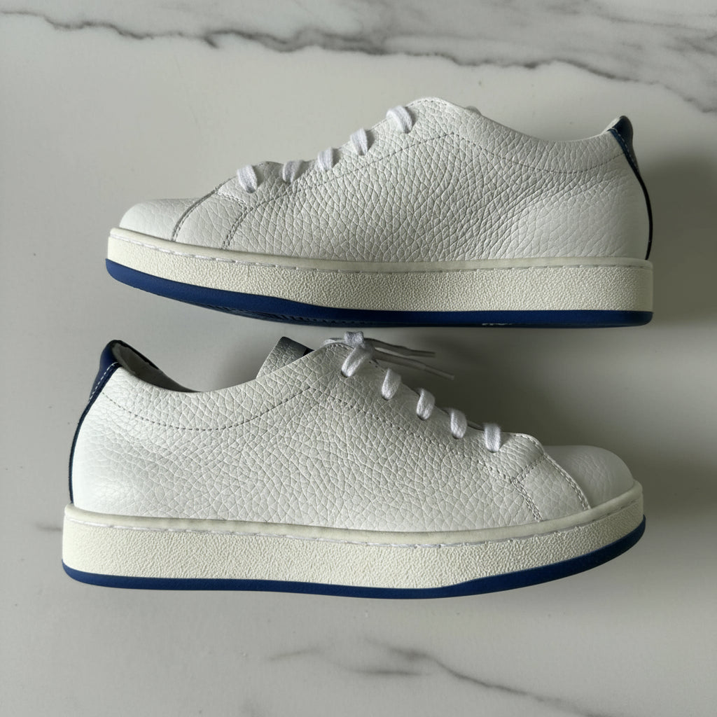 Pair of white sneakers with blue soles on a light gray background