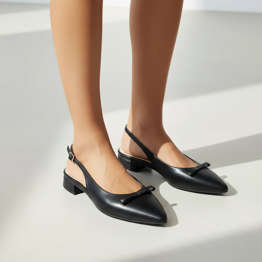 Pair of black leather ANIA slingbacks with pointed toe and 2cm heel on light marble surface.