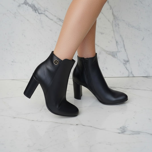 Petite back ankle boots on a marble floor with green plants in the background