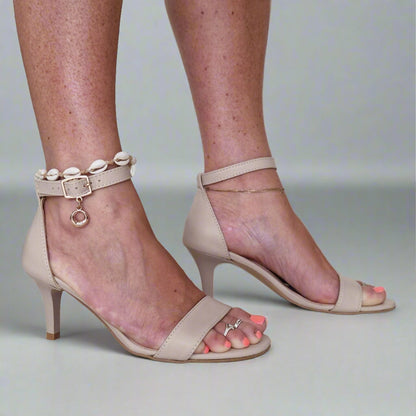 A woman wearing beige leather ankle strap sandals
