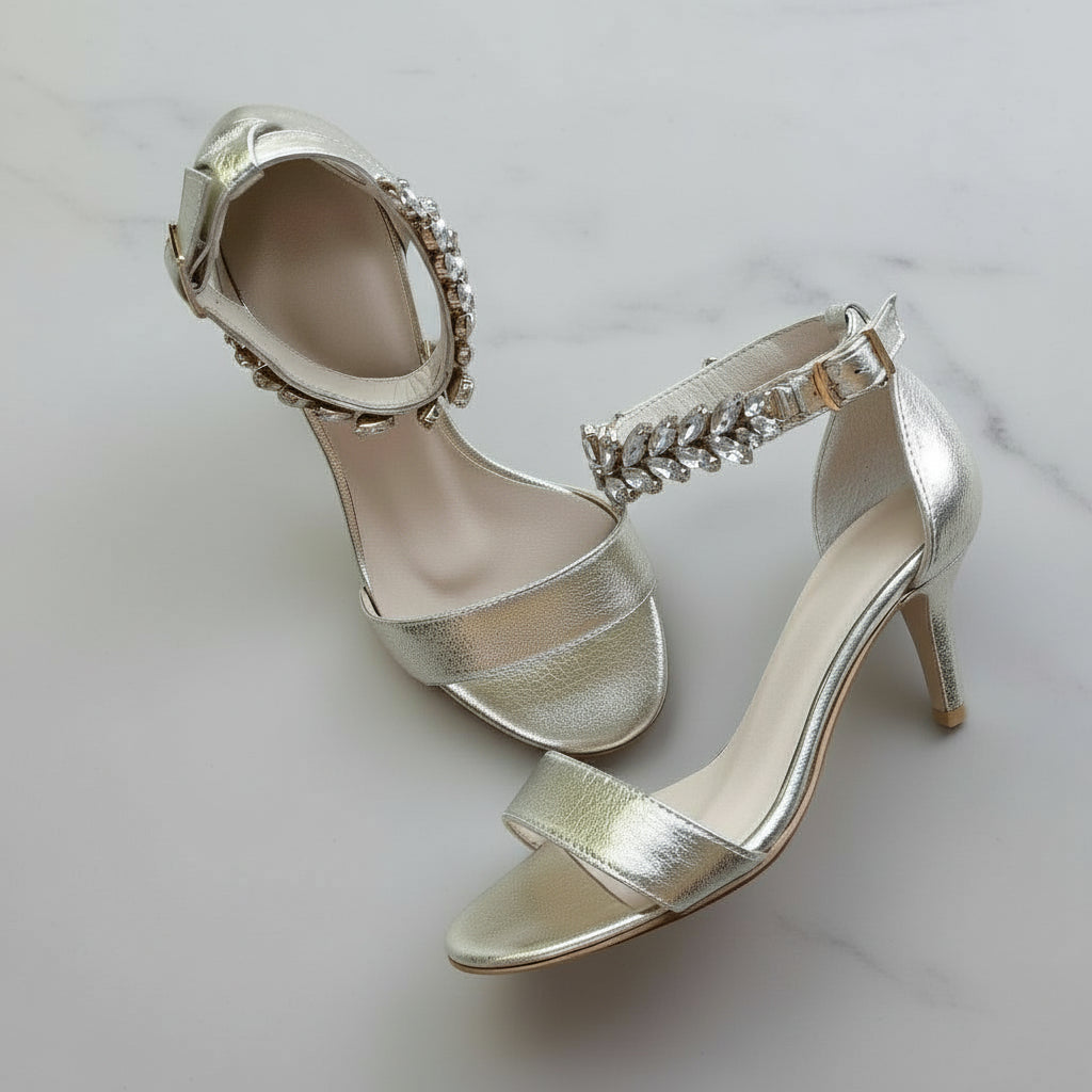 Pair of silver high-heeled shoes with embellishments on a light background