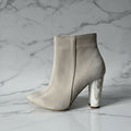 Beige suede ankle boot with a block heel on a grey background
