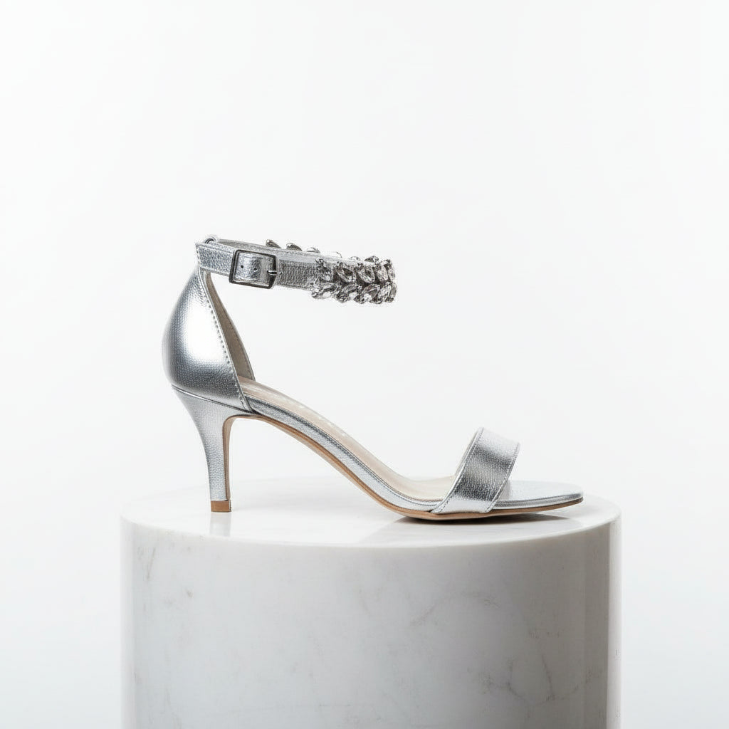 Black high-heeled sandal with a decorative strap on a white pedestal