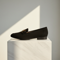 Black loafer shoe on a white pedestal with a neutral background