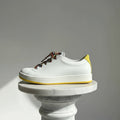 White sneaker with colorful laces on a gray background