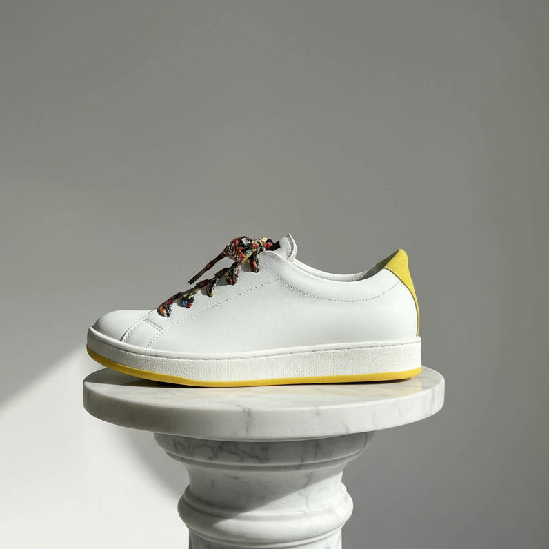 White sneaker with colorful laces on a gray background