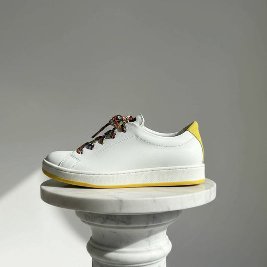 White sneaker with colorful laces on a gray background