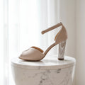 Beige high-heeled shoe on a marble surface with a light background