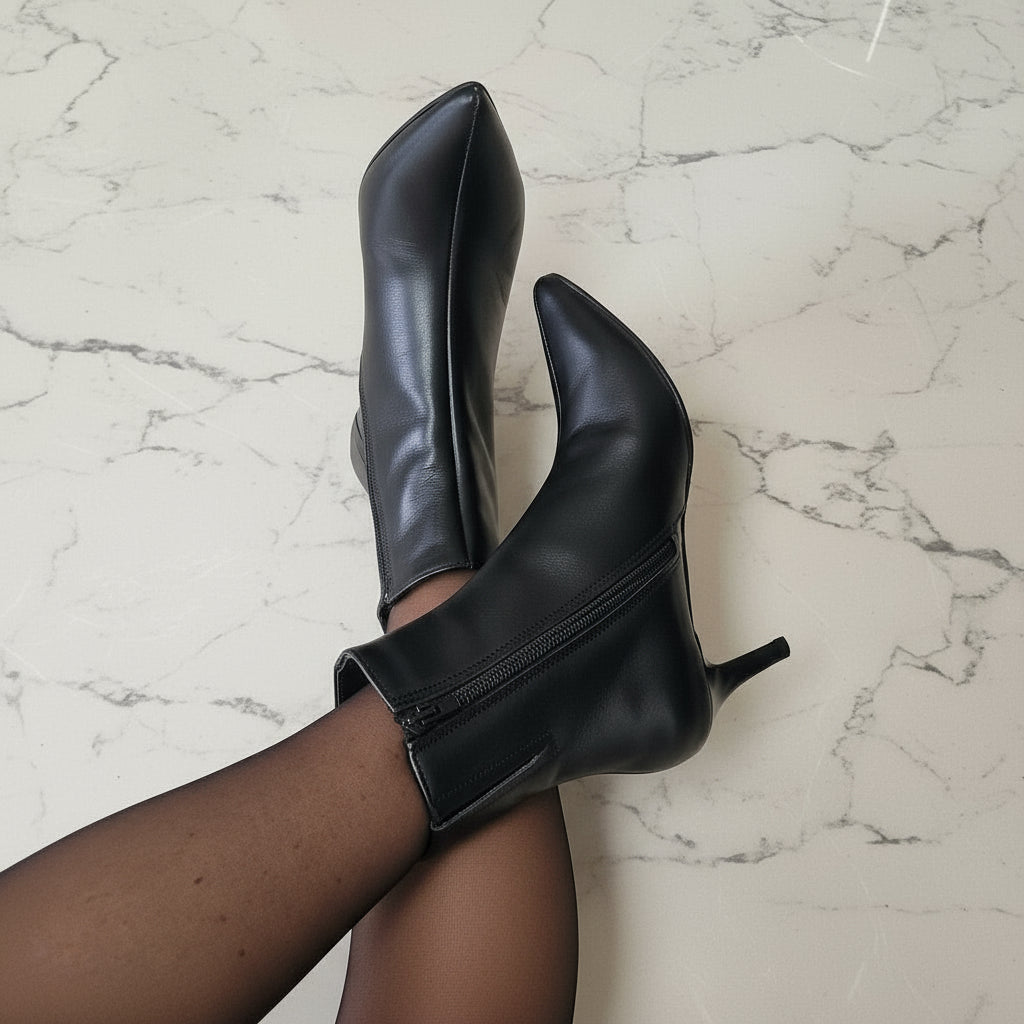 Black high-heeled boots on a marble floor