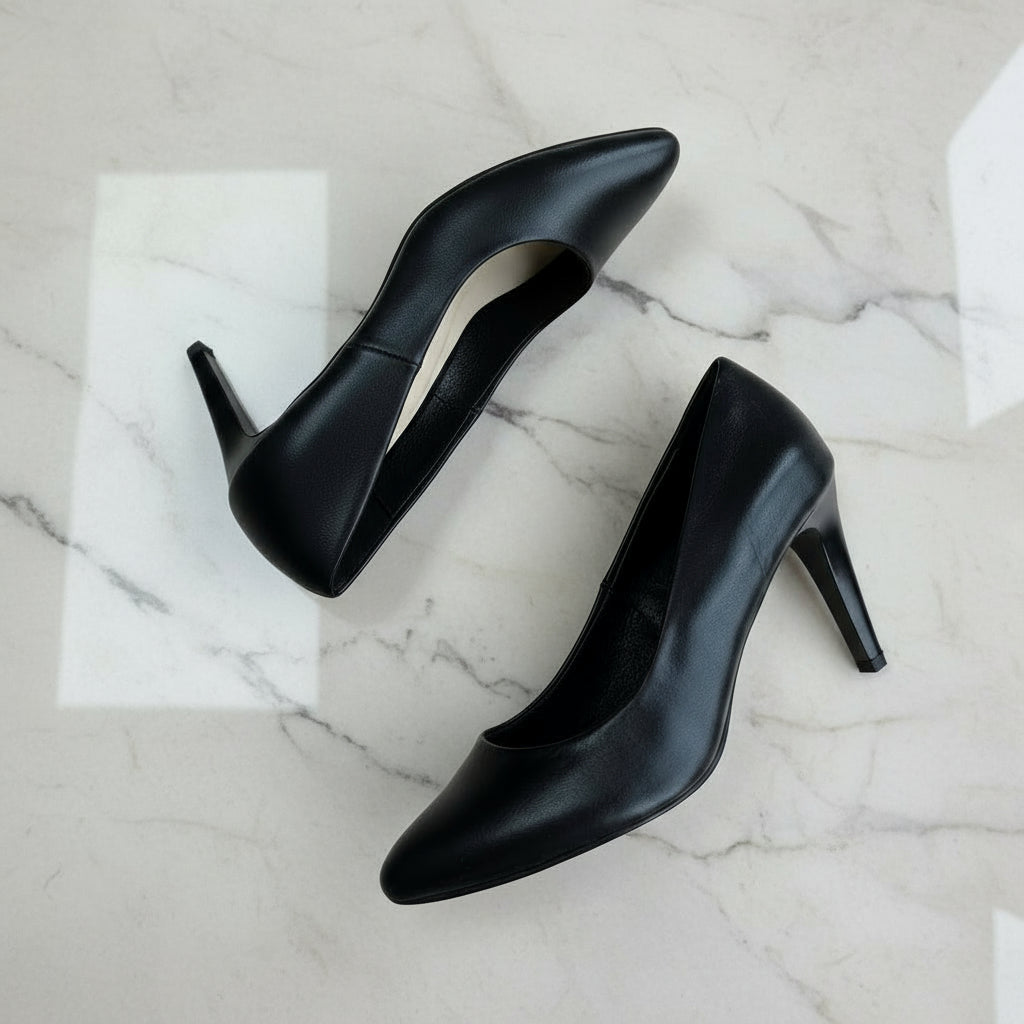 Pair of black high-heeled shoes on a light gray floor.