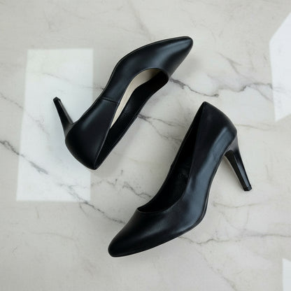 Pair of black high-heeled shoes on a light gray floor.