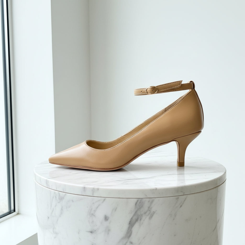 Beige high-heeled shoe on a marble surface with a light background