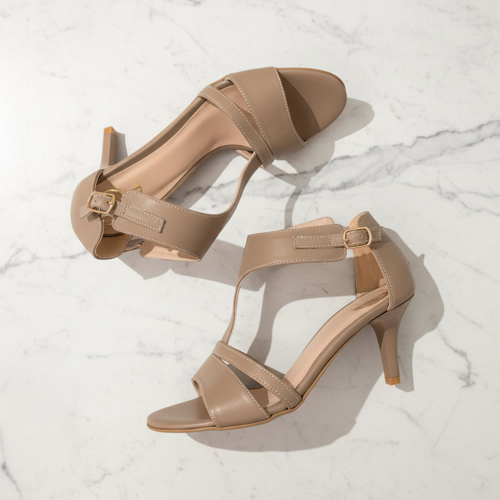 Pair of beige high-heeled sandals on a light marble background