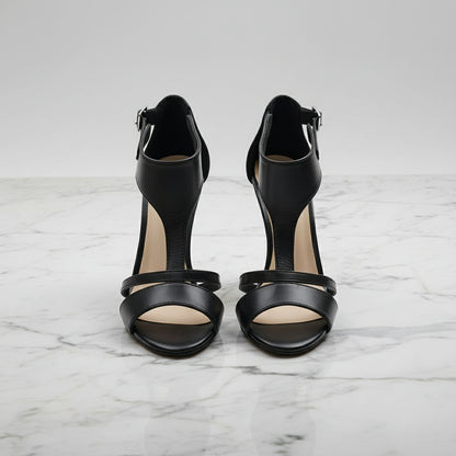Pair of black high-heeled sandals on a marble surface