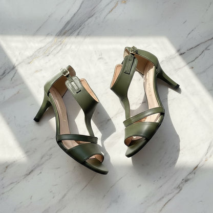 Pair of green high-heeled sandals on a marble surface