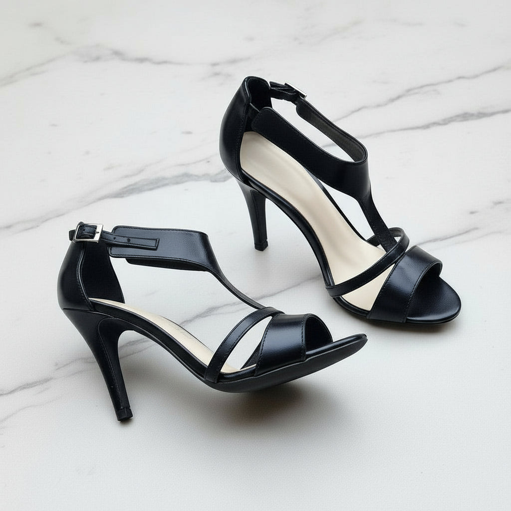 Black high-heeled sandals on a light gray surface
