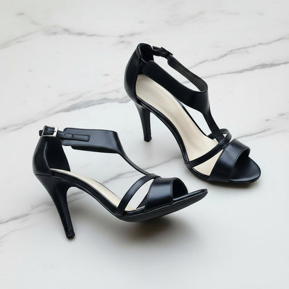 Black high-heeled sandals on a light gray surface