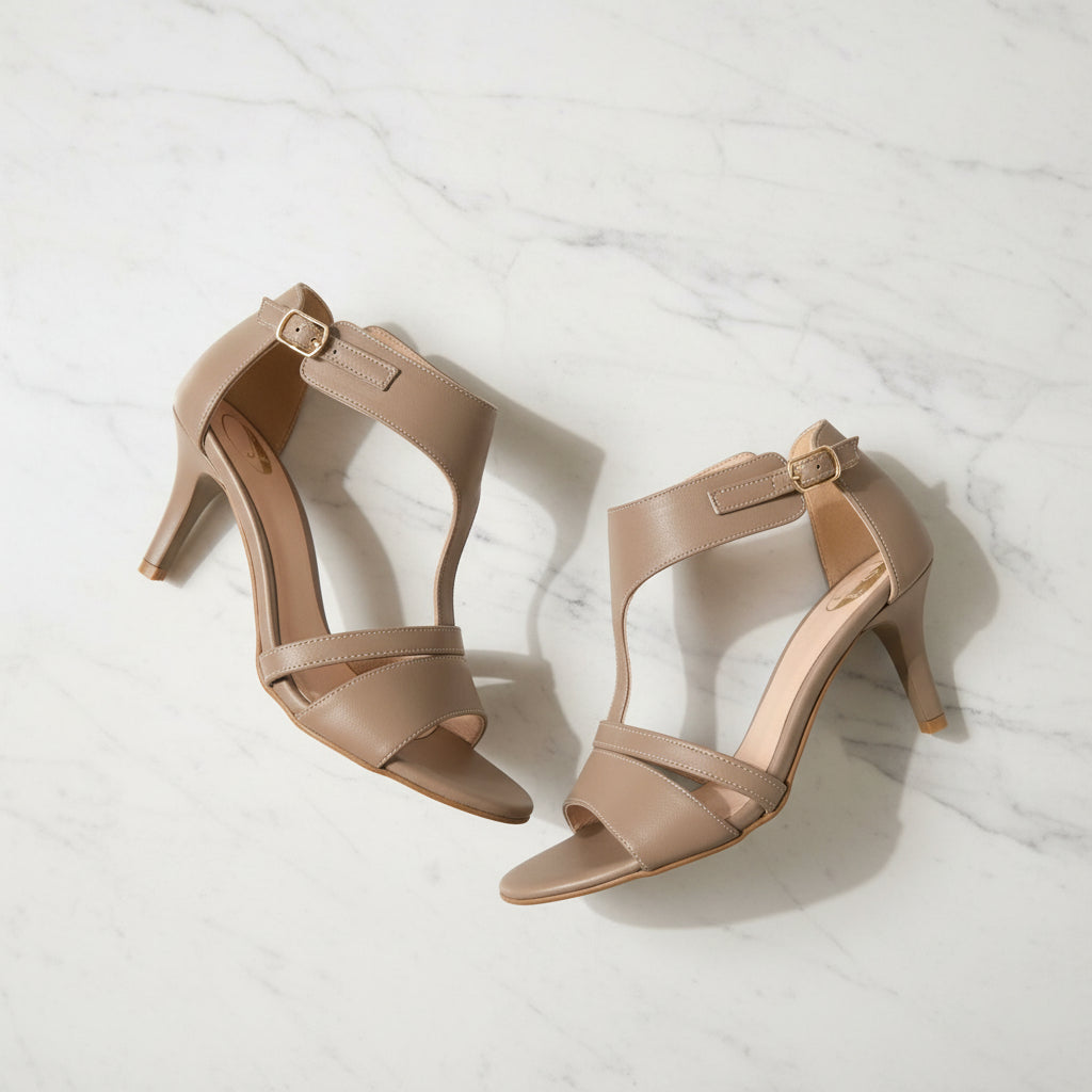 Pair of beige high-heeled sandals on a light marble background