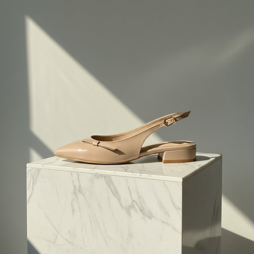Beige slingback shoe on a marble pedestal with a neutral background