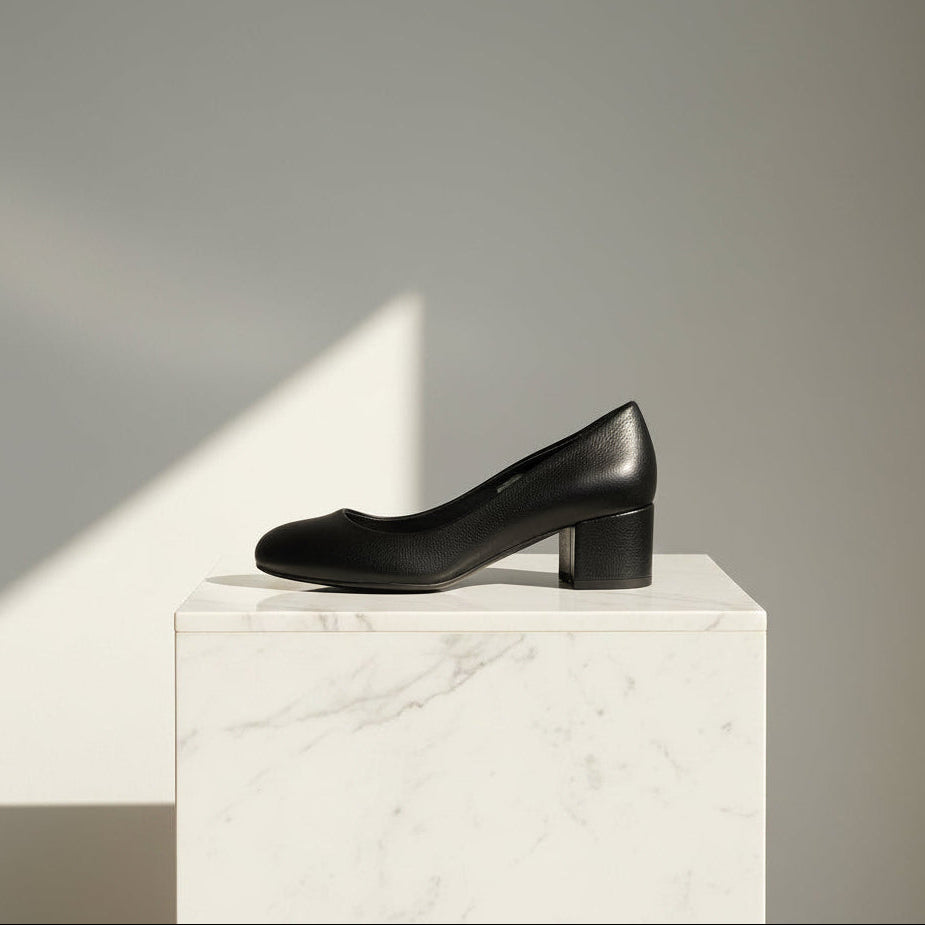 Black leather shoe on a white marble pedestal against a gray background