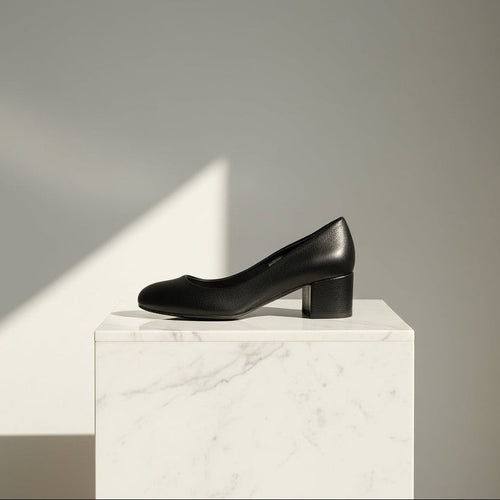 Black leather shoe on a white marble pedestal against a gray background
