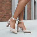 Beige suede ankle strap block heels worn, side view showing sleek silhouette and buckle fastening.