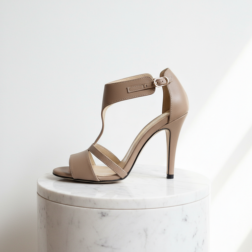 Beige high-heeled sandal on a white marble pedestal with a light gray background