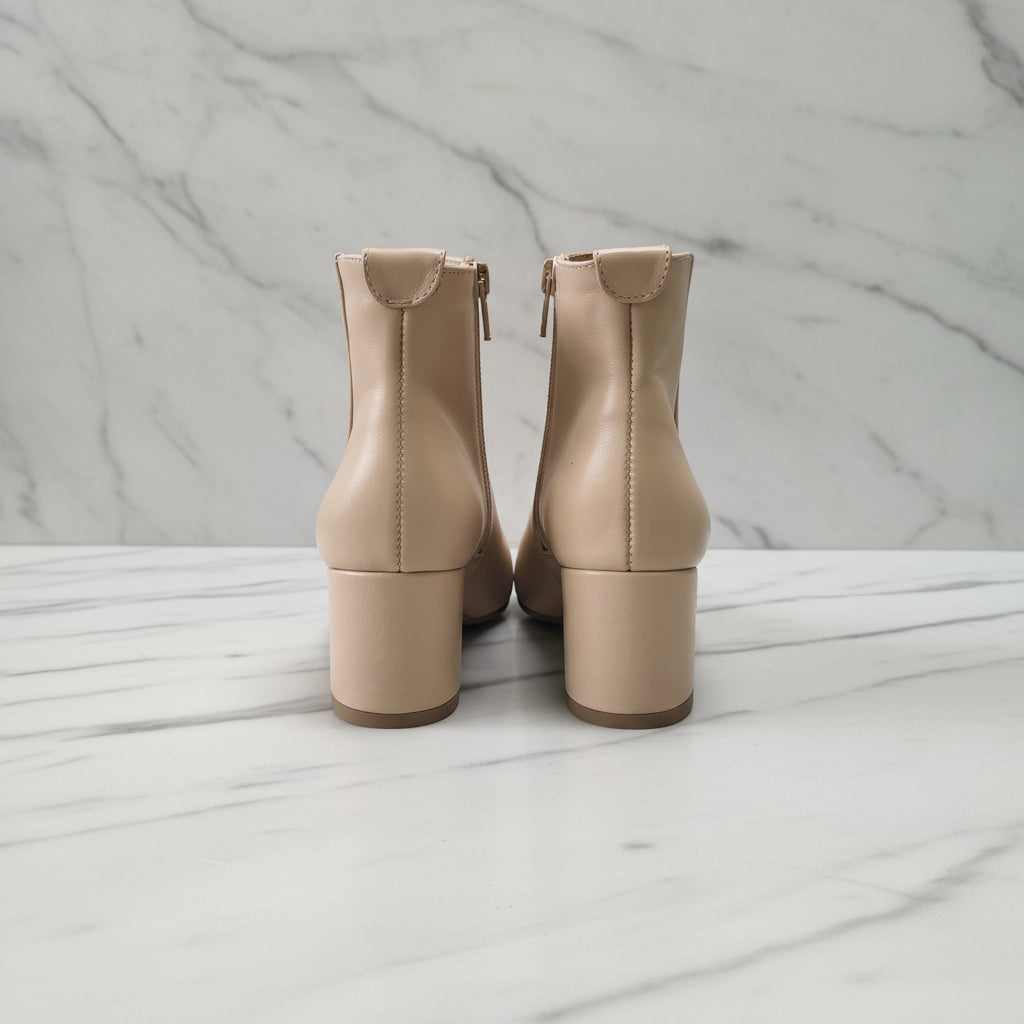 Pair of beige ankle boots on a marble surface