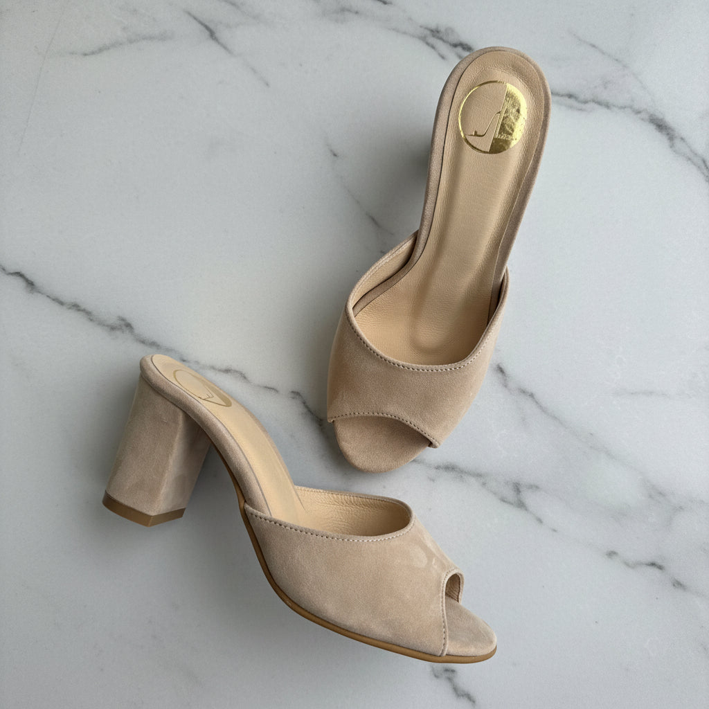 Pair of beige high-heeled shoes on a marble surface