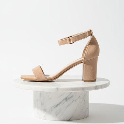 Beige sandal on a marble pedestal against a white background