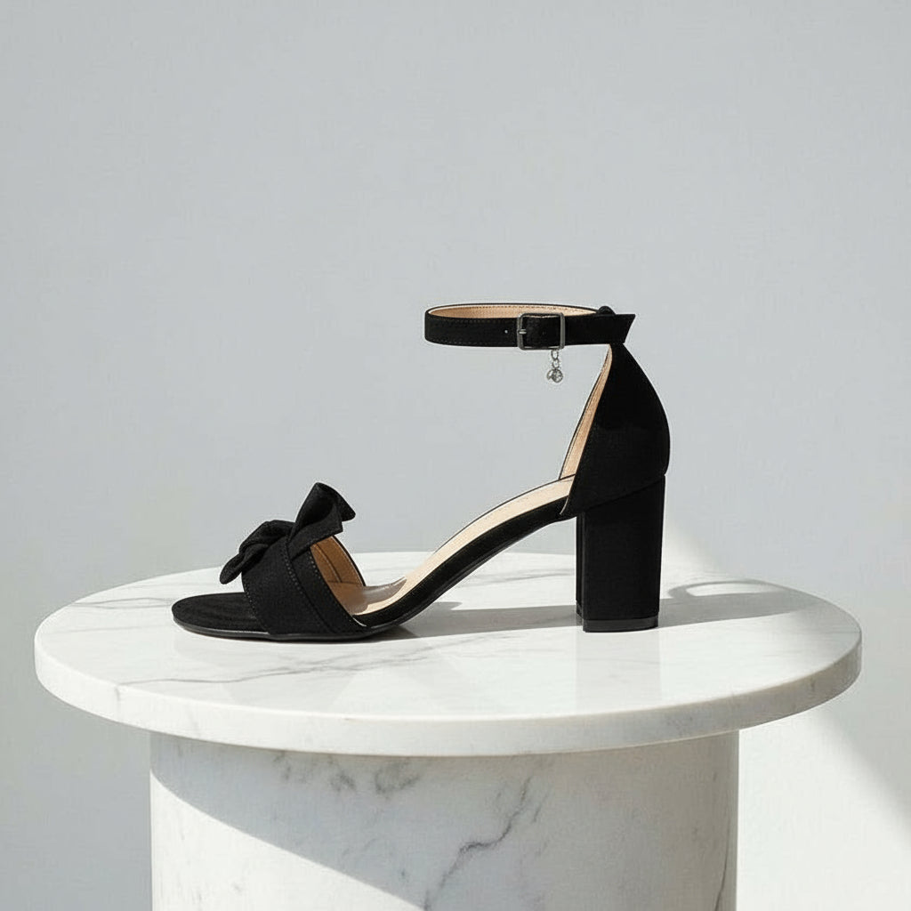 Black sandal on a white marble pedestal against a light gray background