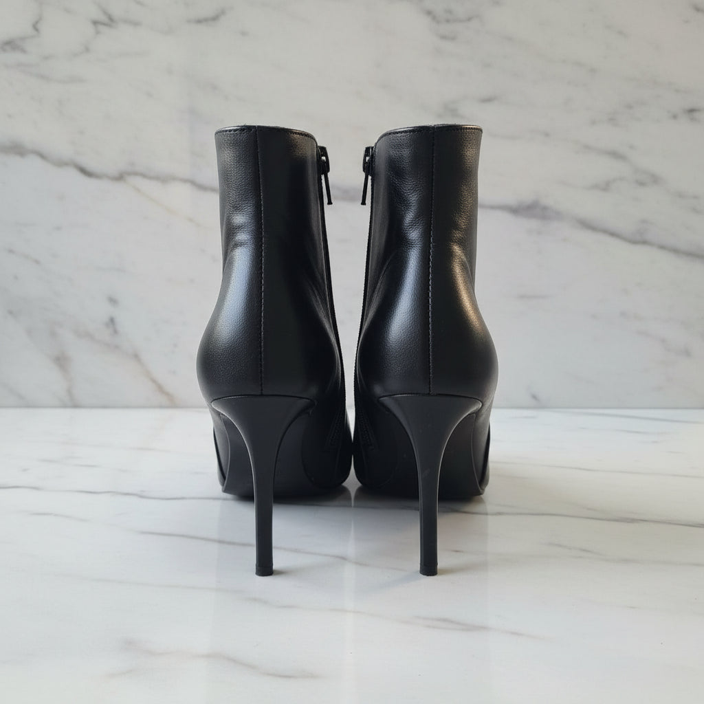 Black high-heeled boots on a gray surface