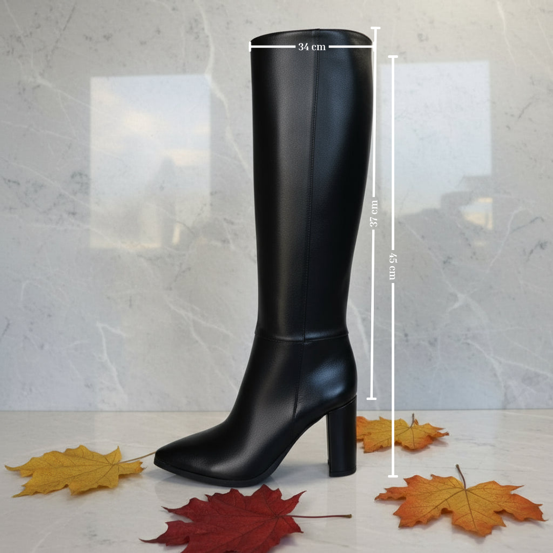 Black knee-high boot with measurements on a light background with autumn leaves.