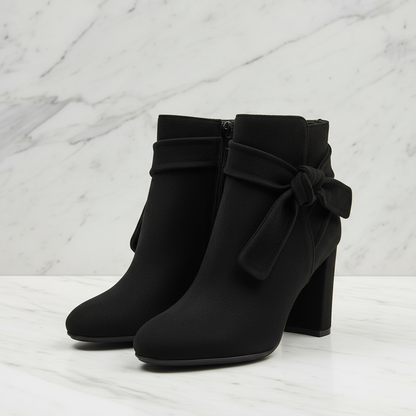 Purple ankle boots with a bow on a light gray background