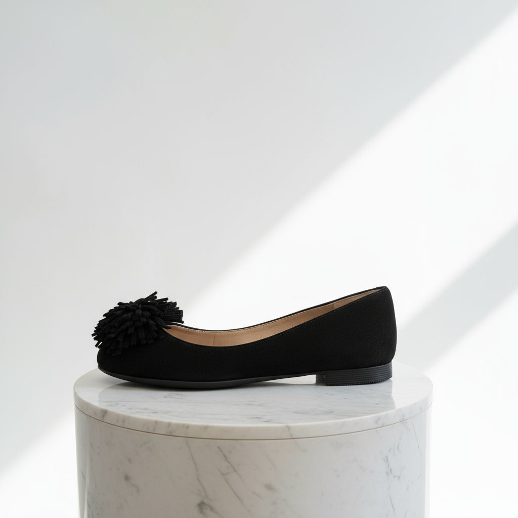 Black flat shoe with a decorative flower on a white background
