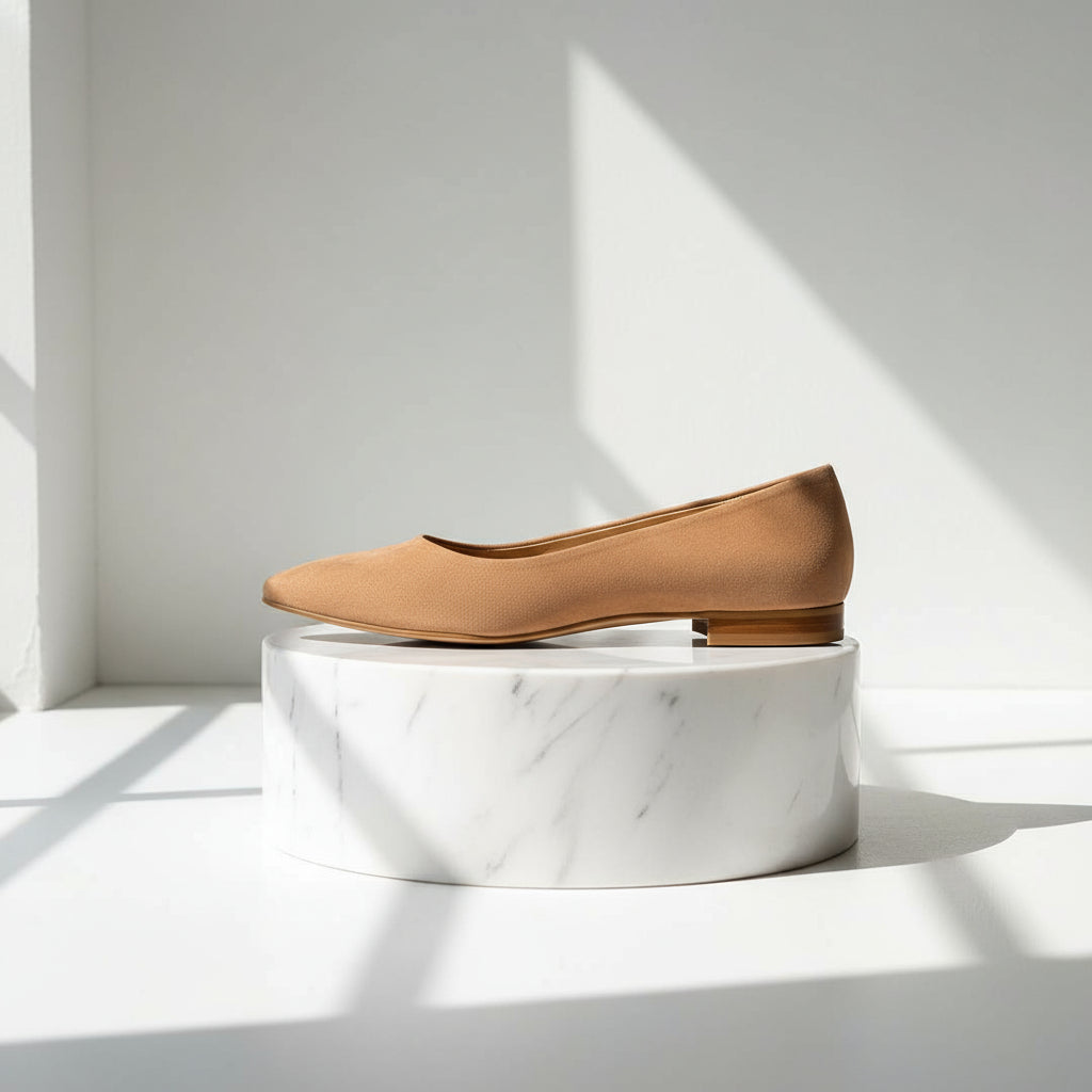 Tan suede flat shoe on a textured gray surface