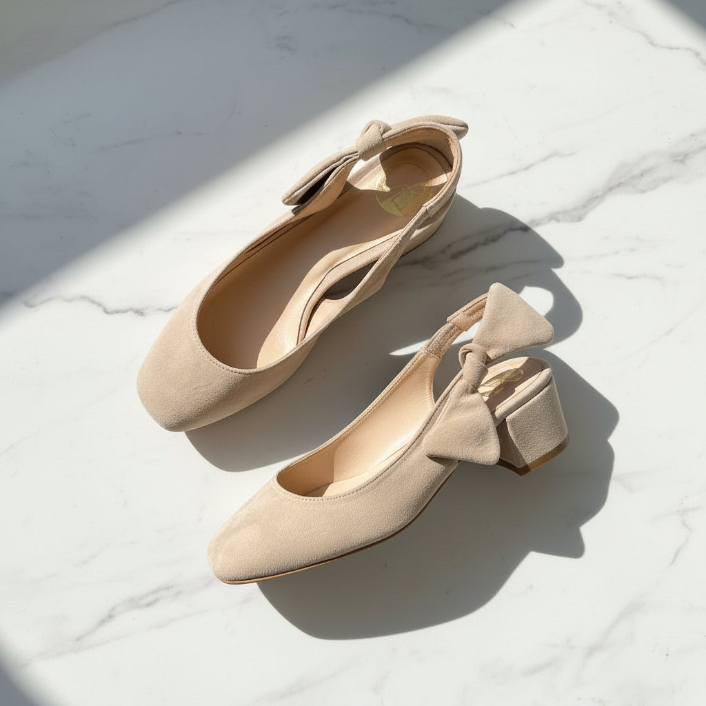 Pair of beige shoes with bow details on a marble surface