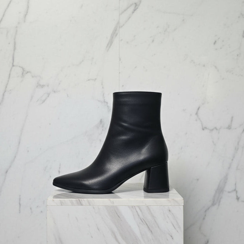 Side view of black pointed toe boots set on a block mid heel.