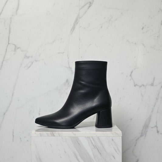 Side view of black pointed toe boots set on a block mid heel.