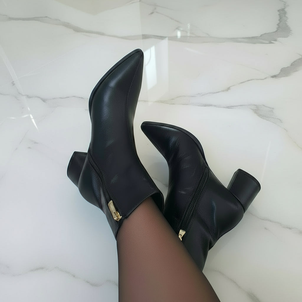 Woman wearing pointed toe petite black leather boots with a block heel.
