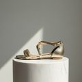 Gold sandal on a white pedestal against a gray background