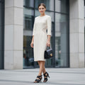 Black strappy high-heeled sandals on a light gray marble background