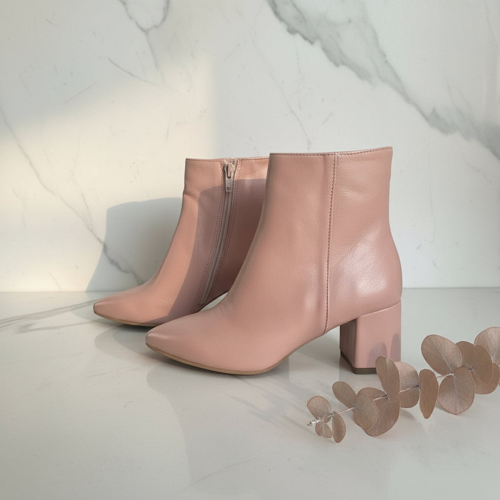 Pair of pink ankle boots on a reflective marble floor.