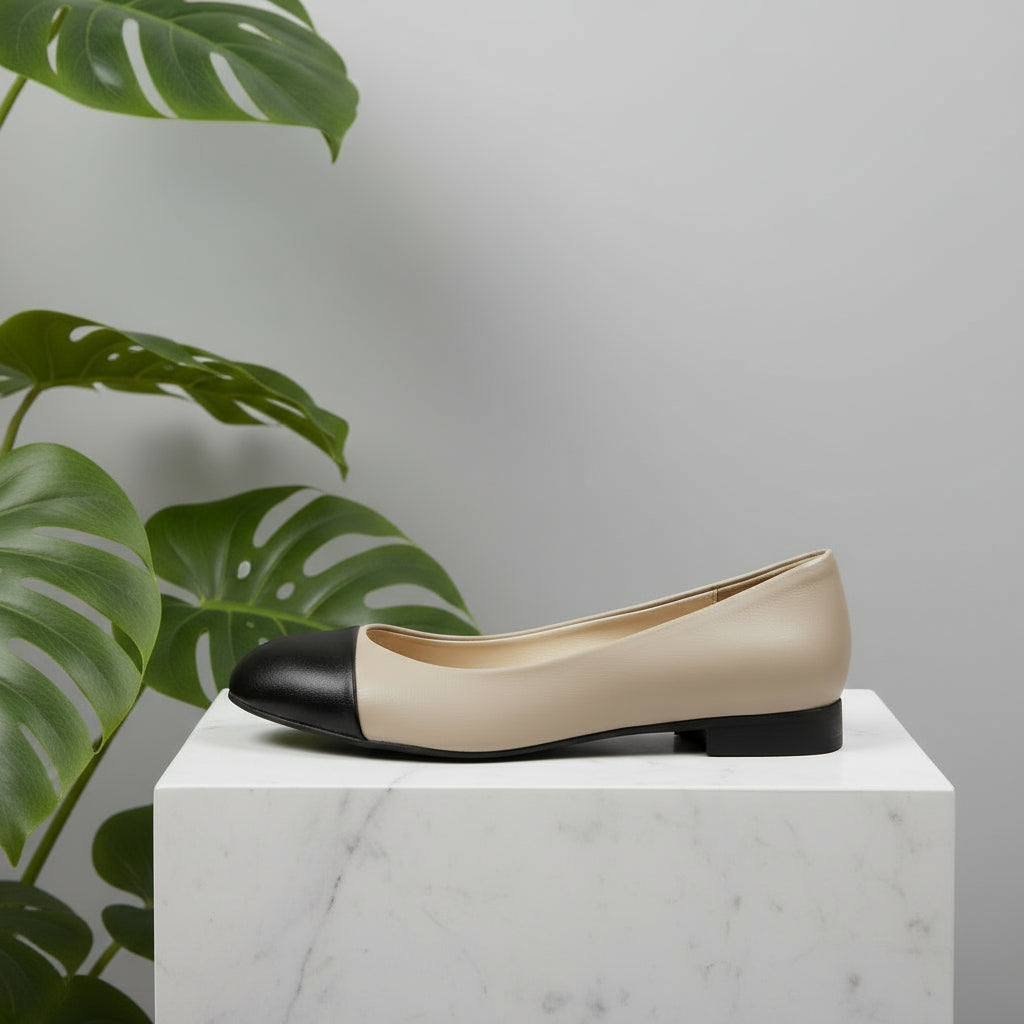 Black and beige shoe on a white surface with a gray concrete background