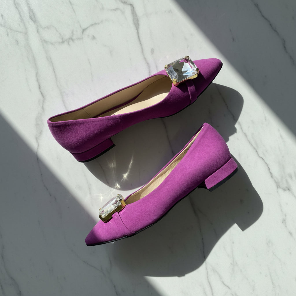 Purple shoes with crystal embellishments on a marble surface