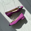 Purple shoes with crystal embellishments on a marble surface