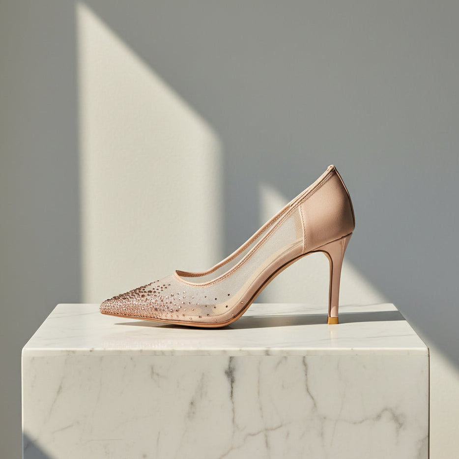 Nude high-heeled petite wedding or occasion shoes with mesh and crystal upper on a marble pedestal. 