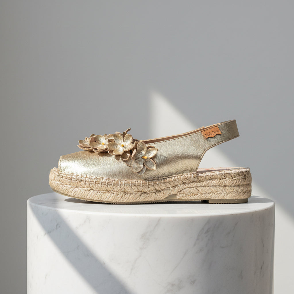 Gold sandal with floral design on a marble pedestal against a gray background
