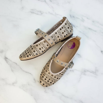 Pair of beige flats with brown polka dot pattern on a marble surface