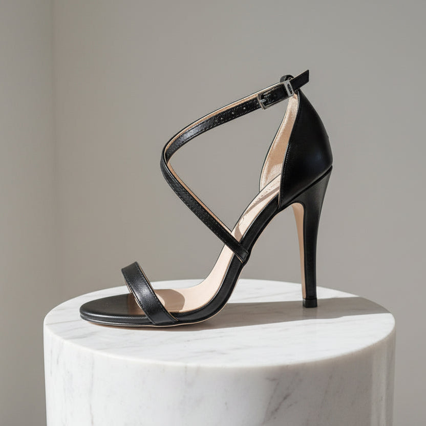 Black high-heeled sandal on a marble pedestal with a neutral background